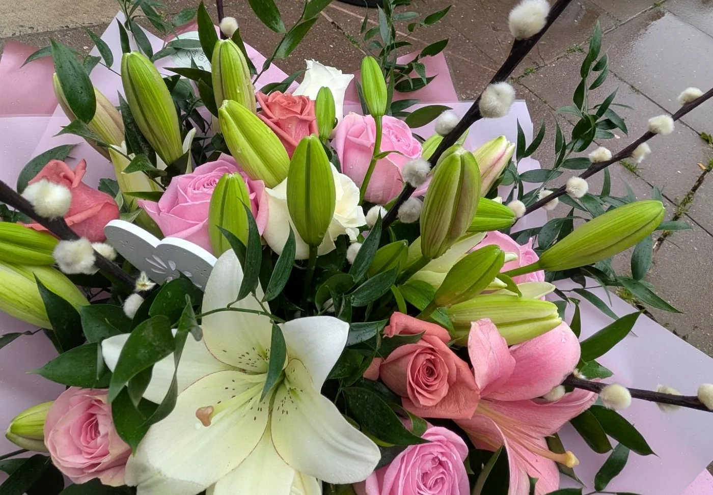 A hand-tied bouquet of pink and white roses and lilies made by The Flower Girl